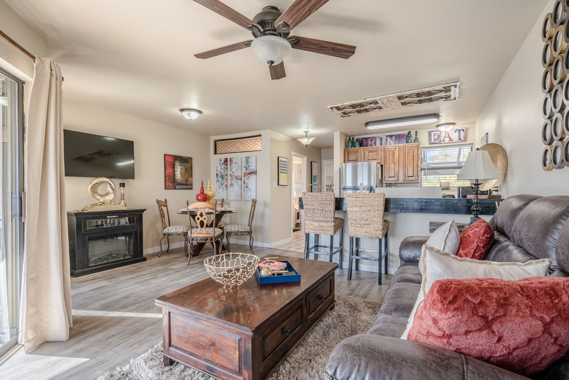 A living room with a couch , coffee table , television and ceiling fan.