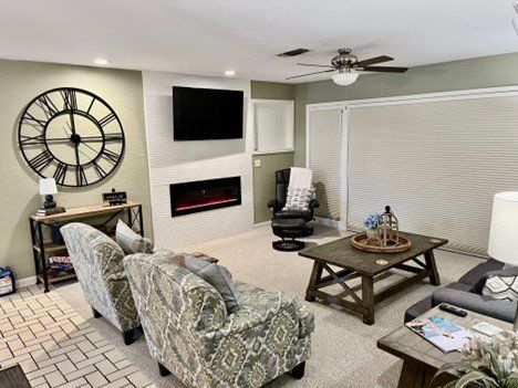 A living room with a fireplace , two couches , a coffee table , and a clock on the wall.