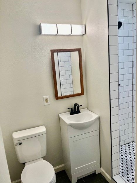 A bathroom with a toilet , sink and mirror