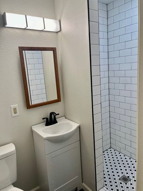 A bathroom with a sink , toilet , mirror and shower.