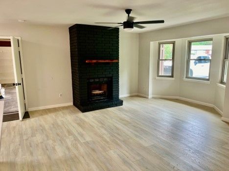 An empty living room with a fireplace and a ceiling fan.