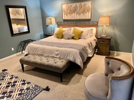 A bedroom with a bed , chair , lamps , and a mirror.