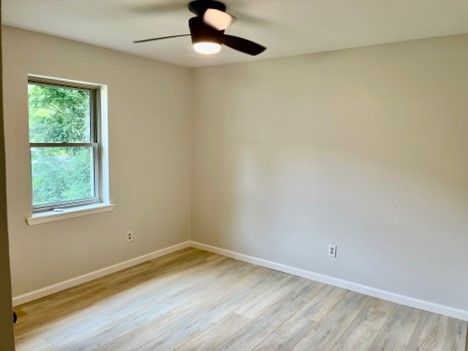 An empty bedroom with a ceiling fan and a window.