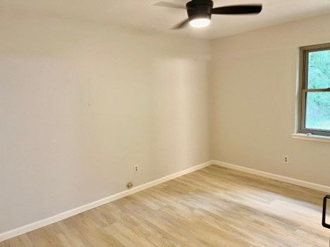 An empty room with a ceiling fan and a window.