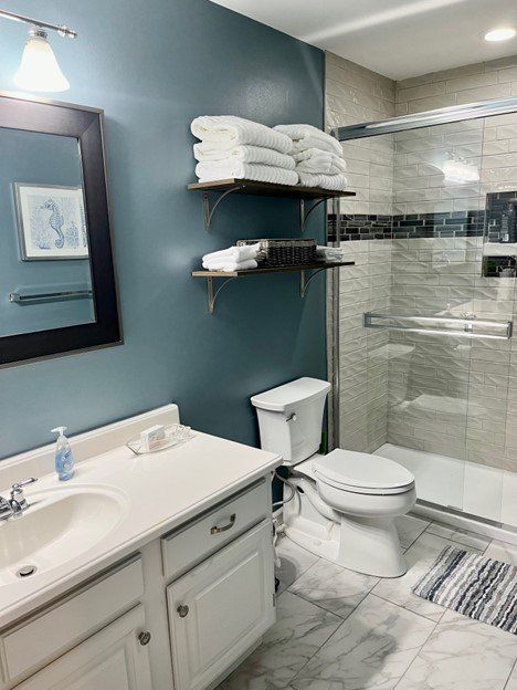 A bathroom with a toilet , sink , mirror and shower.