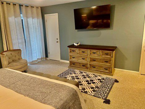 A bedroom with a bed , dresser , chair and television.