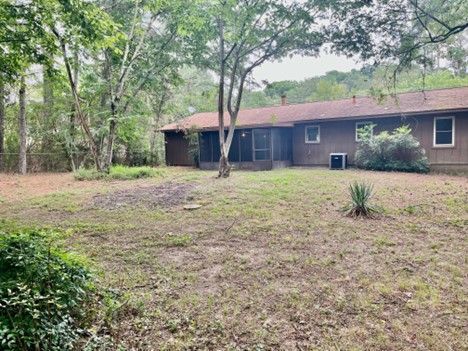 The backyard of a house with a lot of grass and trees in the background.