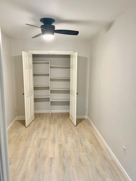 An empty room with a ceiling fan and shelves.