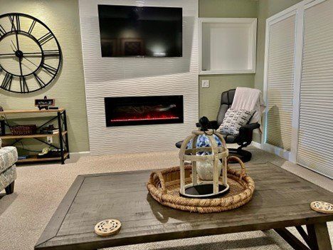 A living room with a fireplace and a clock on the wall.