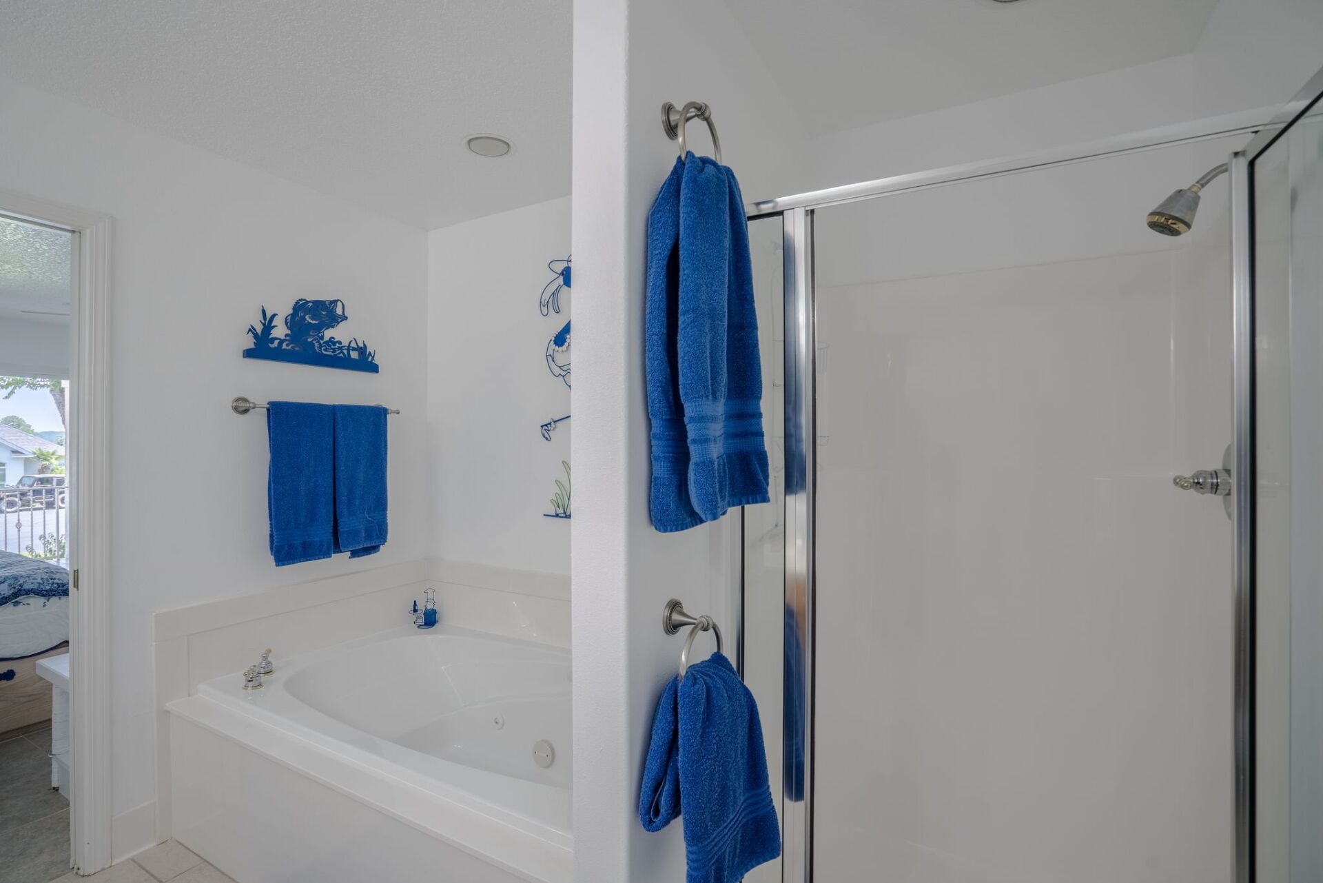 A bathroom with a tub , shower , and blue towels hanging on the wall.