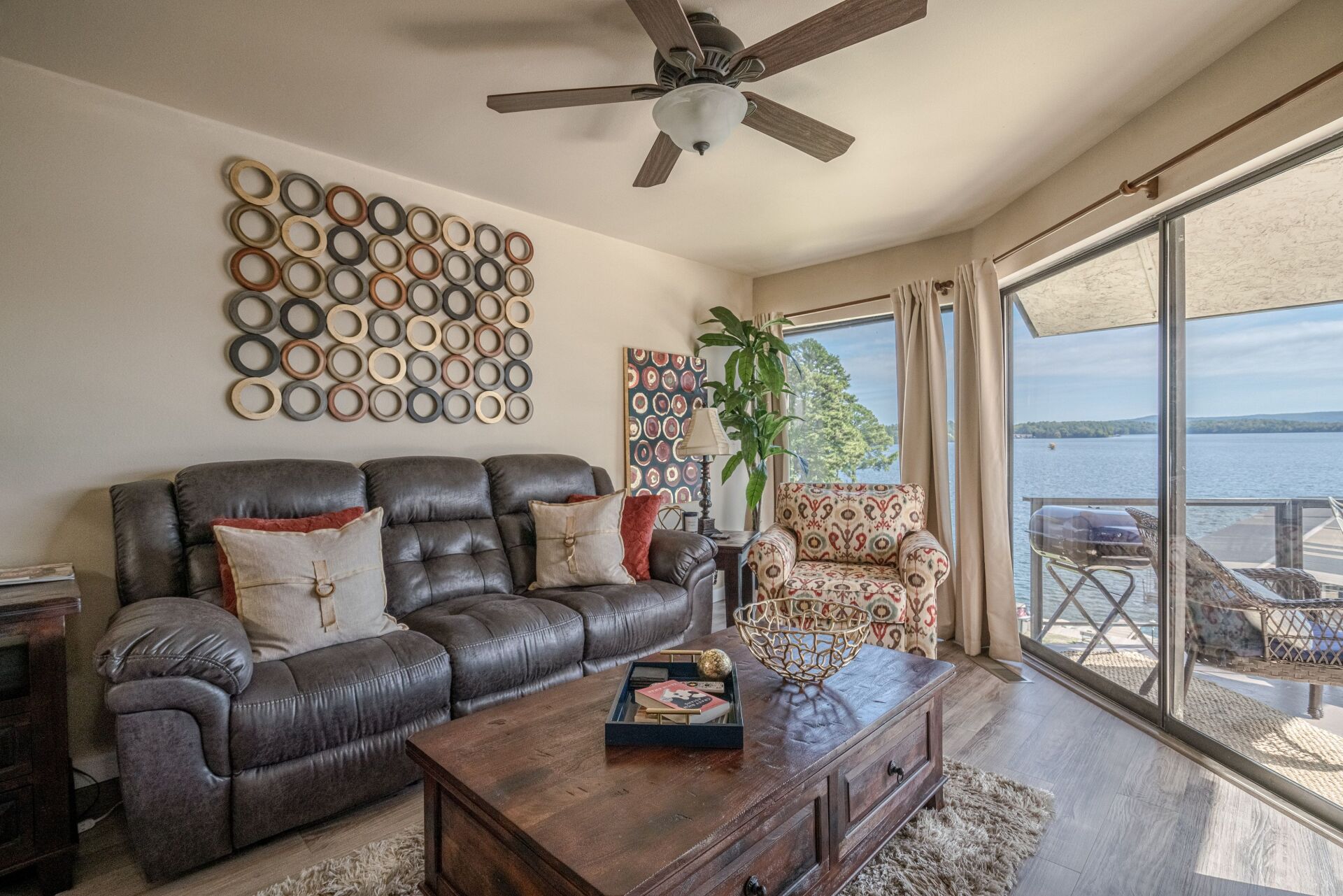 A living room with a couch , chair , coffee table and ceiling fan.