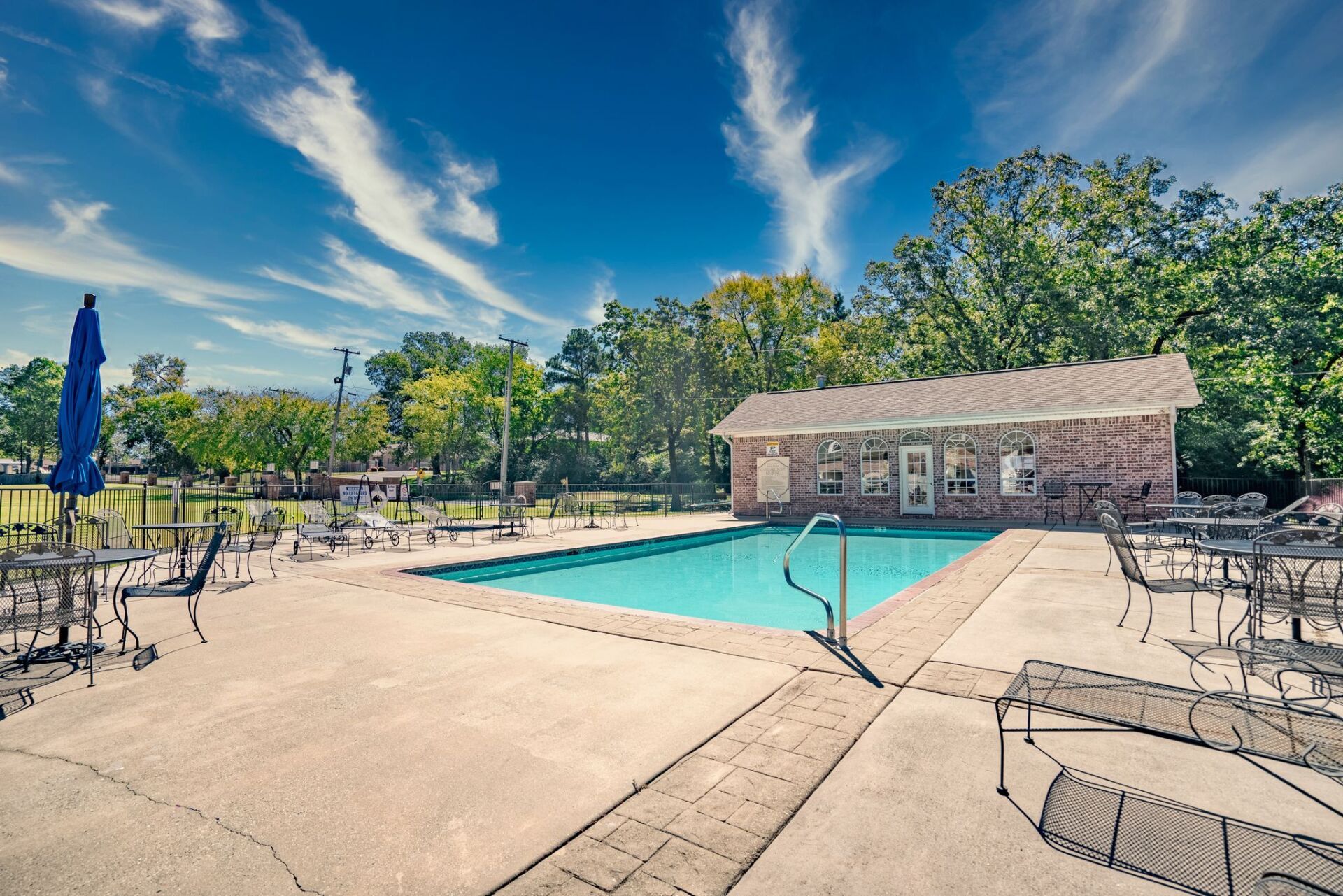A large swimming pool with tables and chairs around it
