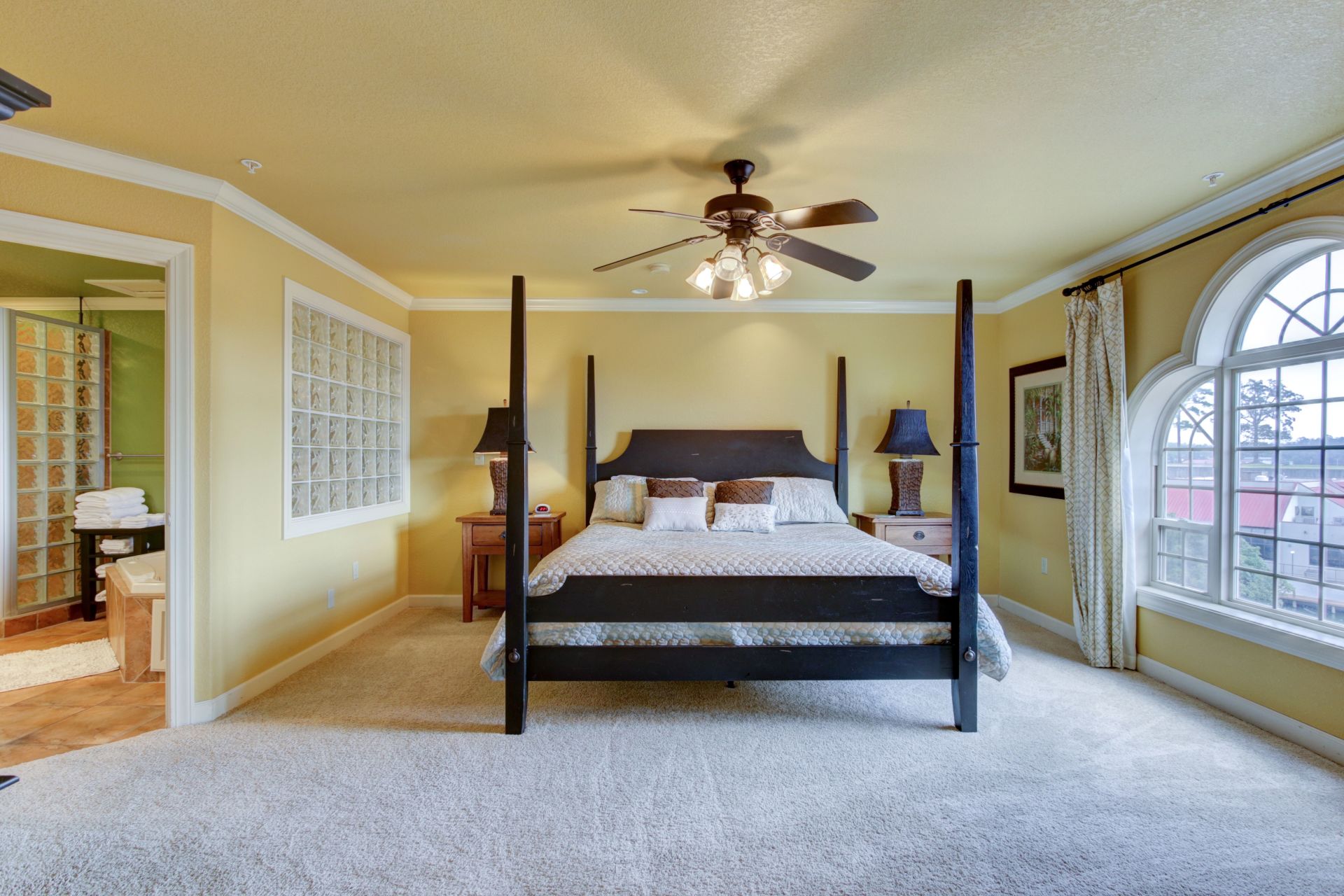 A bedroom with a four poster bed and a ceiling fan