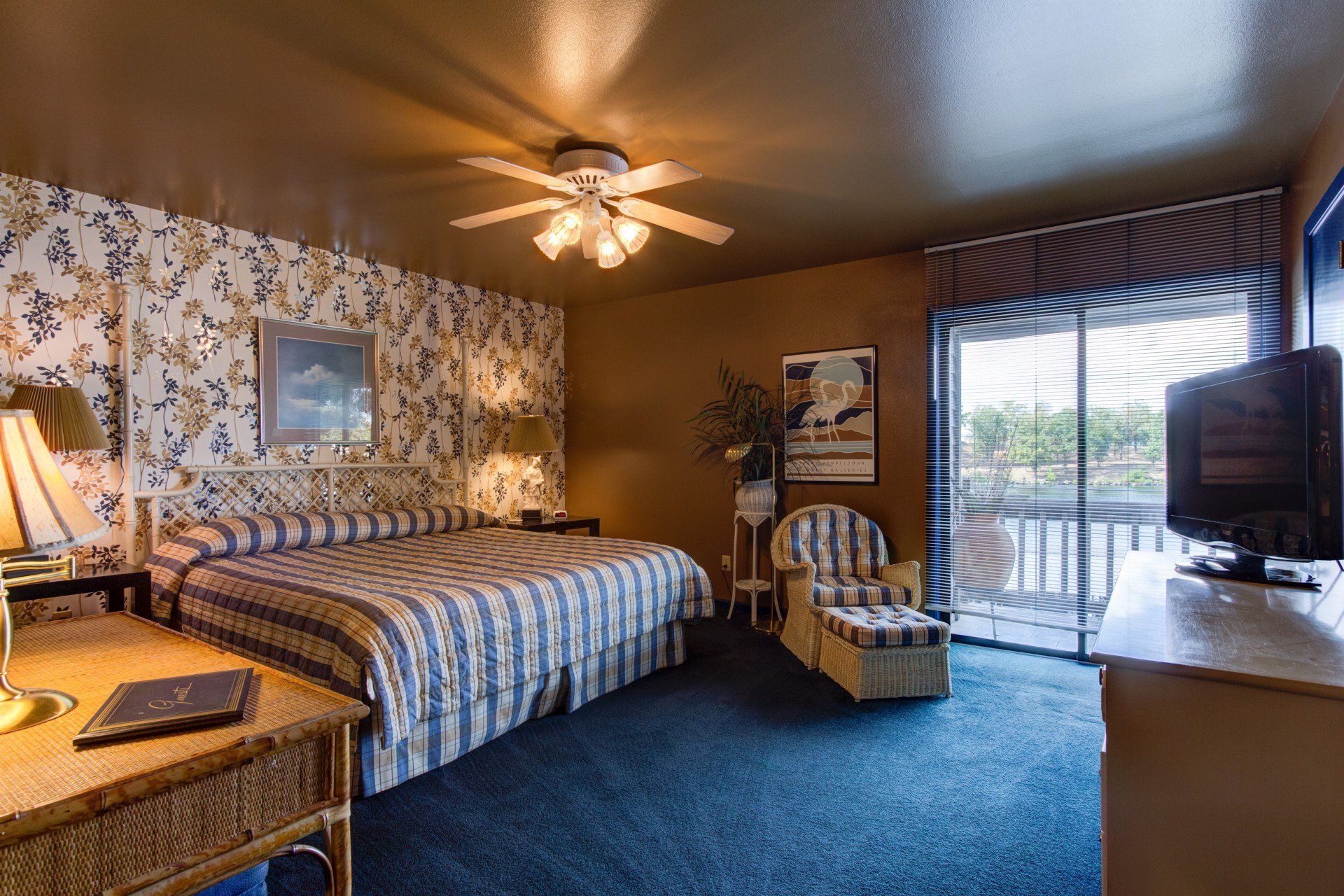 A hotel room with a bed , chair , desk and television.