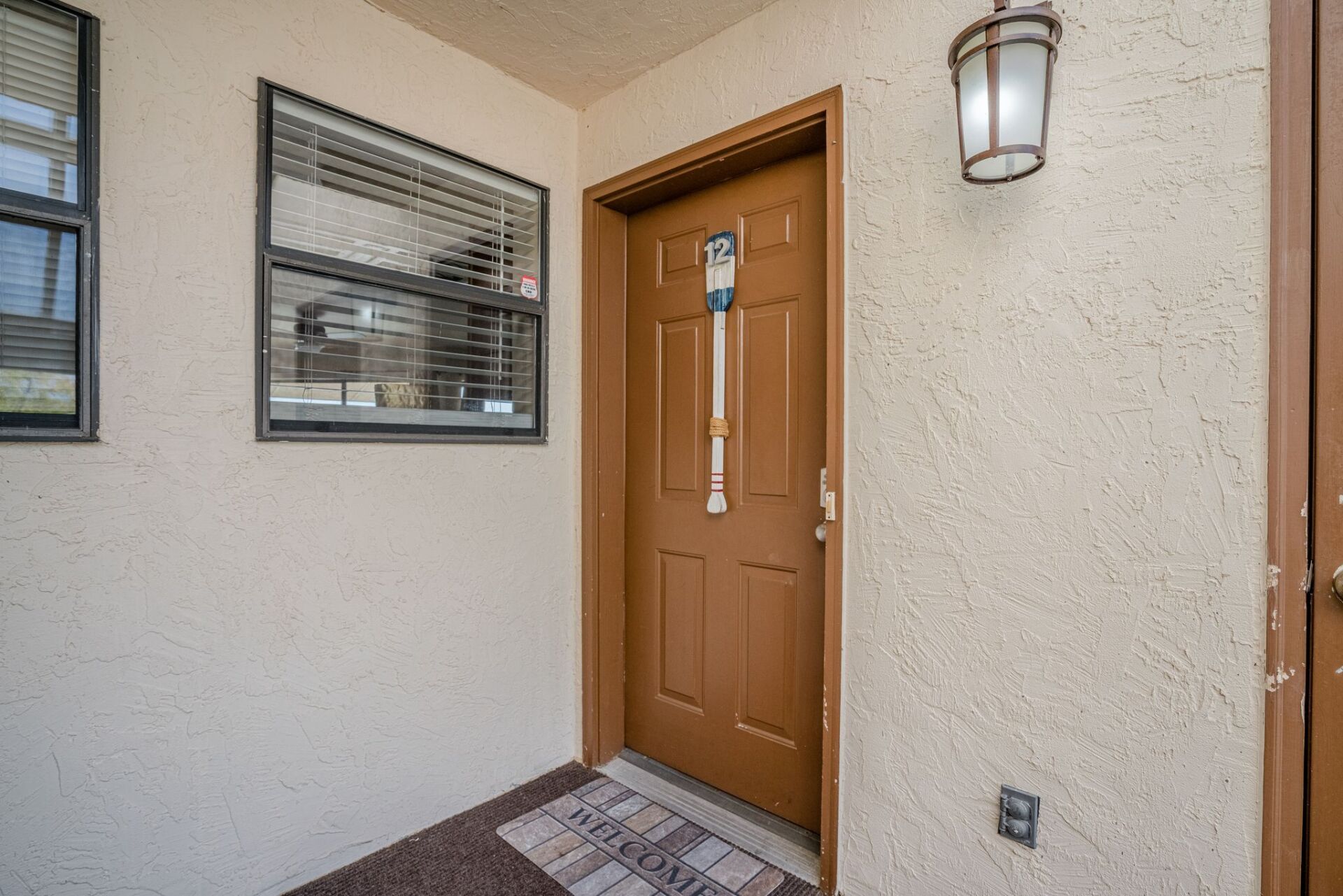 A brown door is sitting on a white wall next to a window.