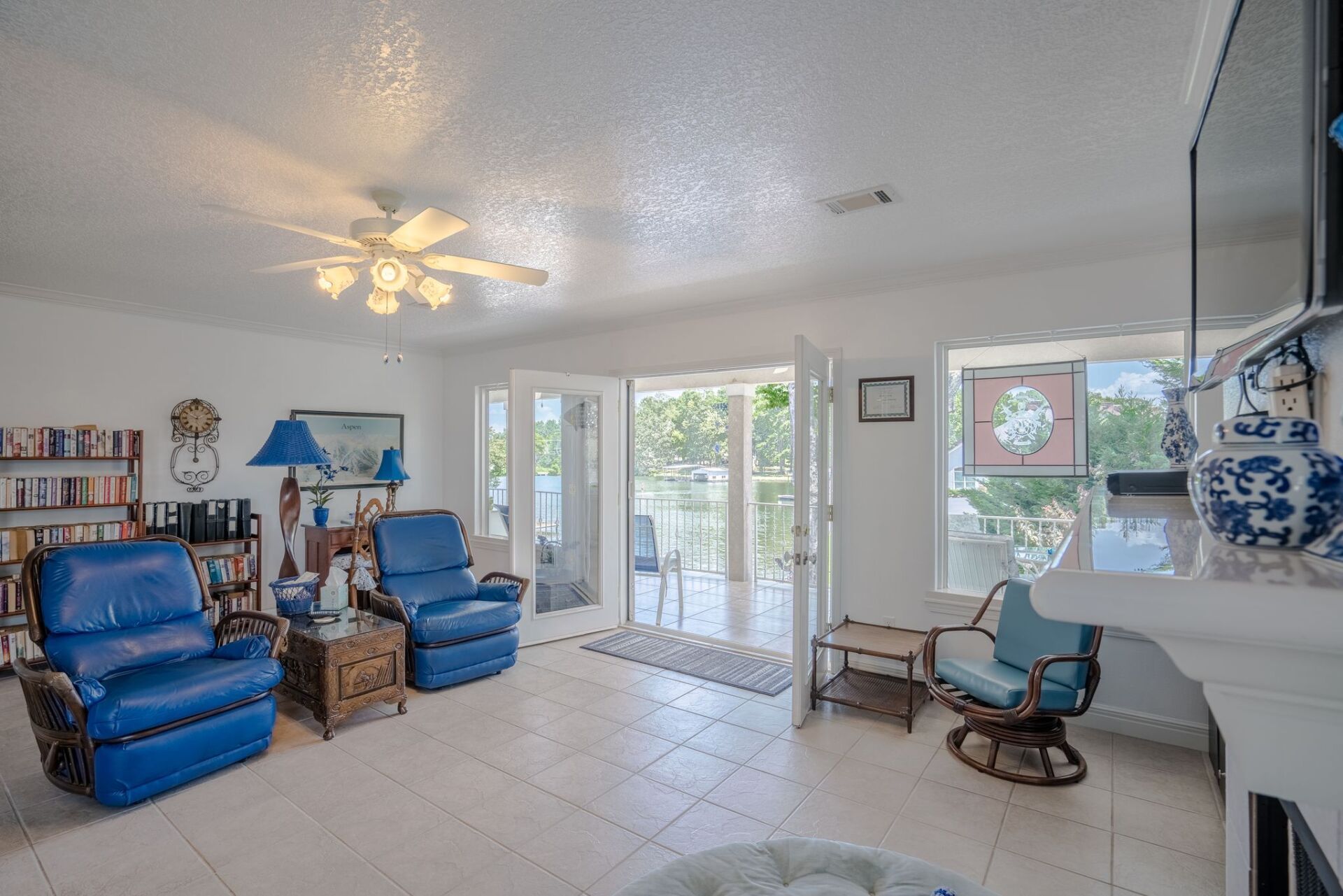 A living room with blue chairs and a ceiling fan.