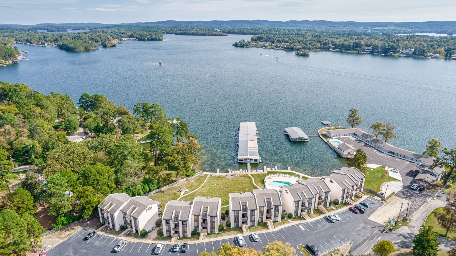 An aerial view of a lake with a dock and houses in the foreground.