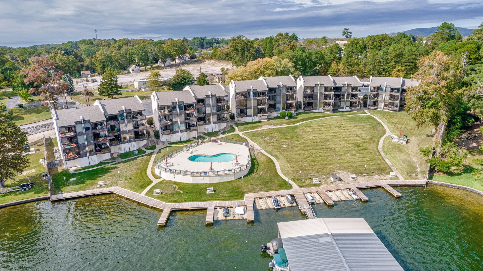 An aerial view of a lake with a dock and buildings in the background.