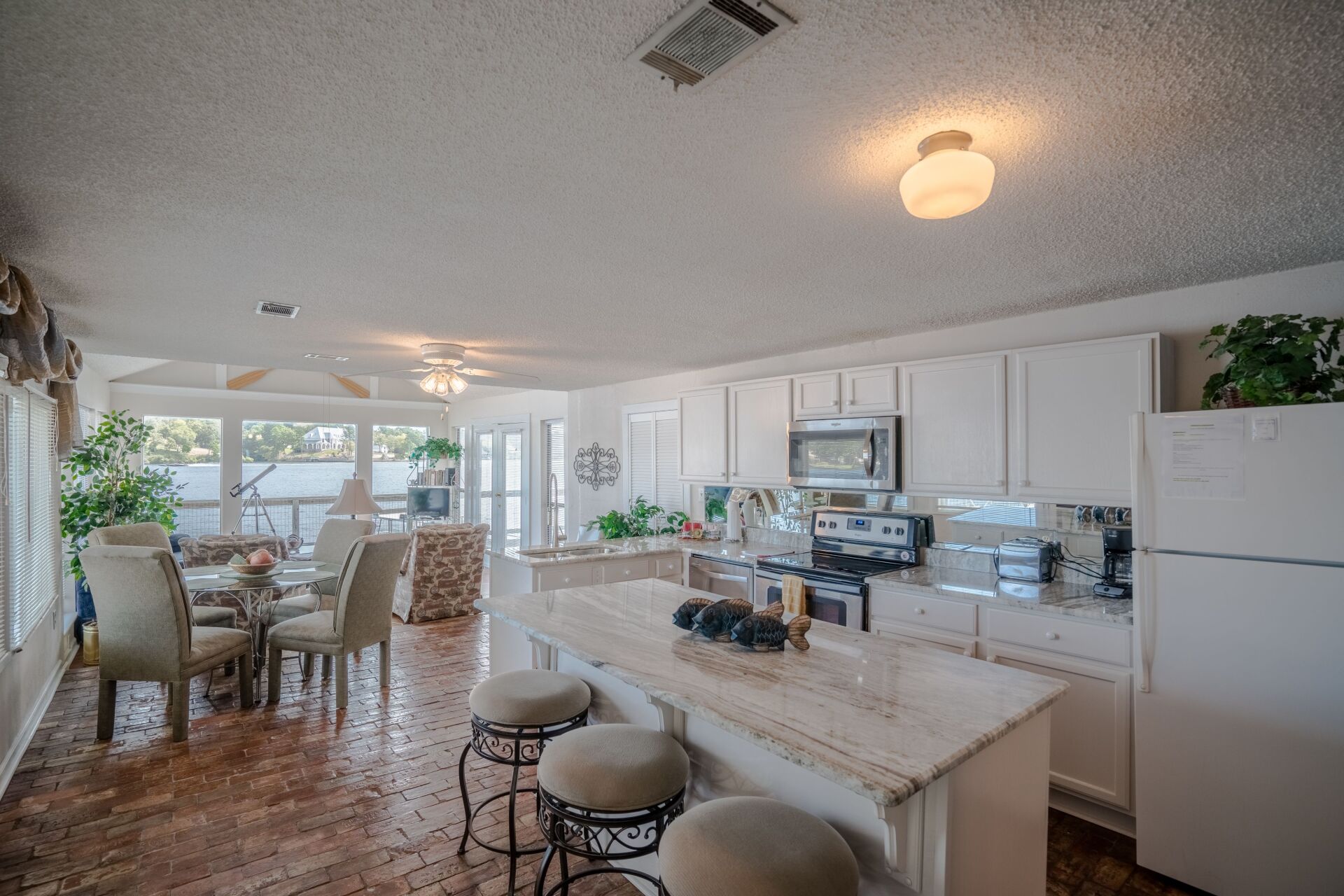 A kitchen with a large island , stools and a refrigerator.