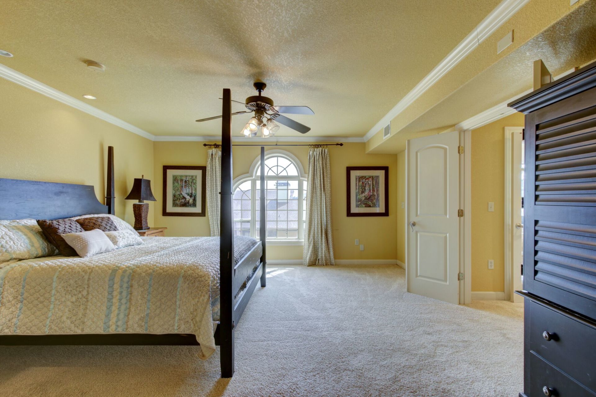 A bedroom with a four poster bed and a ceiling fan