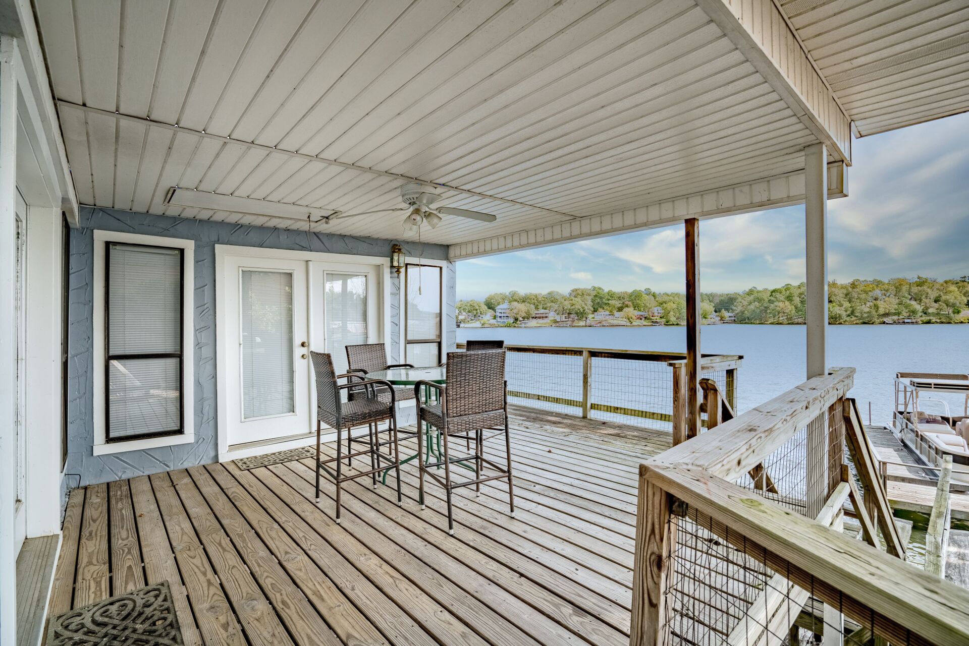 A large deck with a table and chairs overlooking a lake.