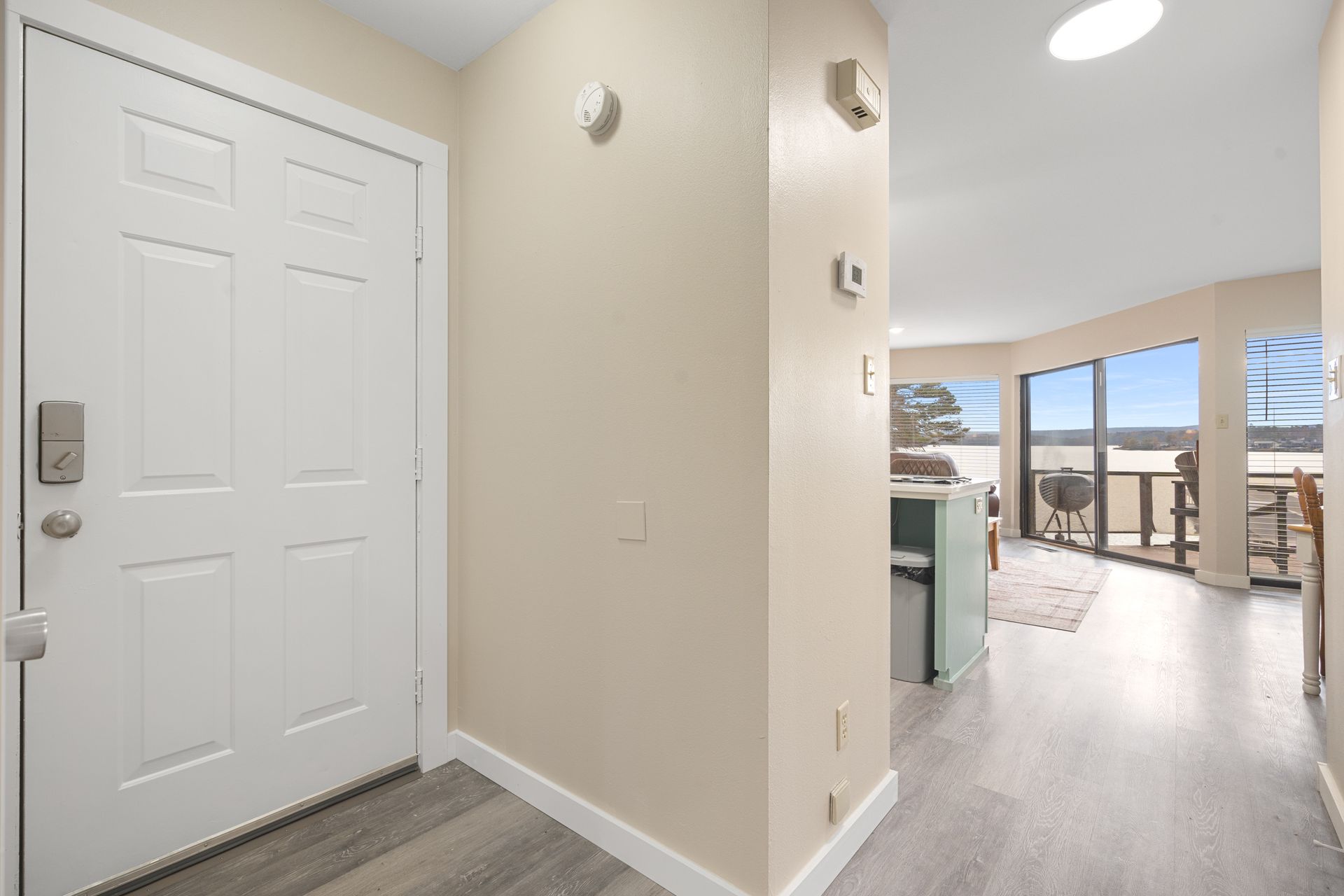 A hallway in a house with a white door and a large window.