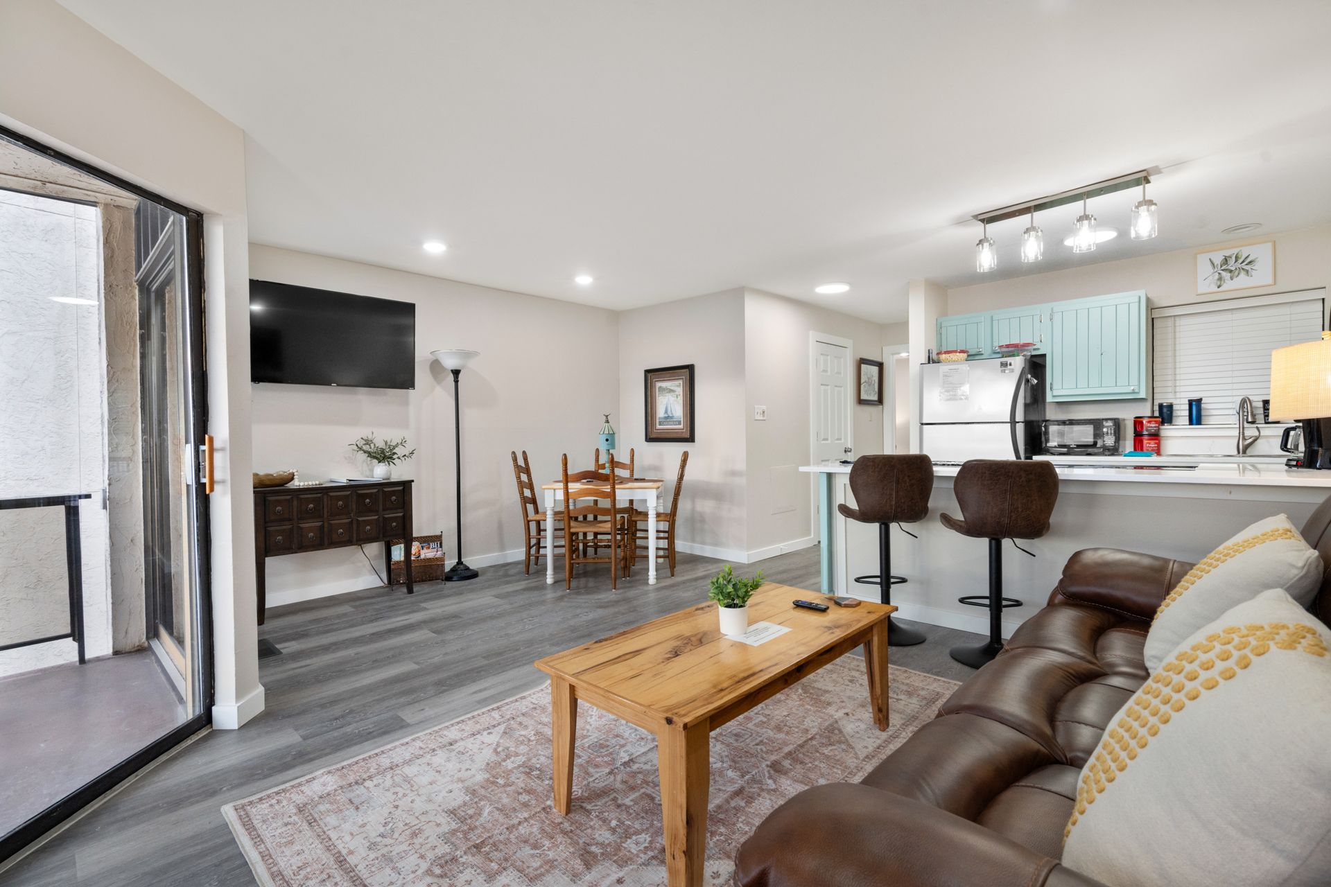 A living room with a couch , table , chairs and a flat screen tv.