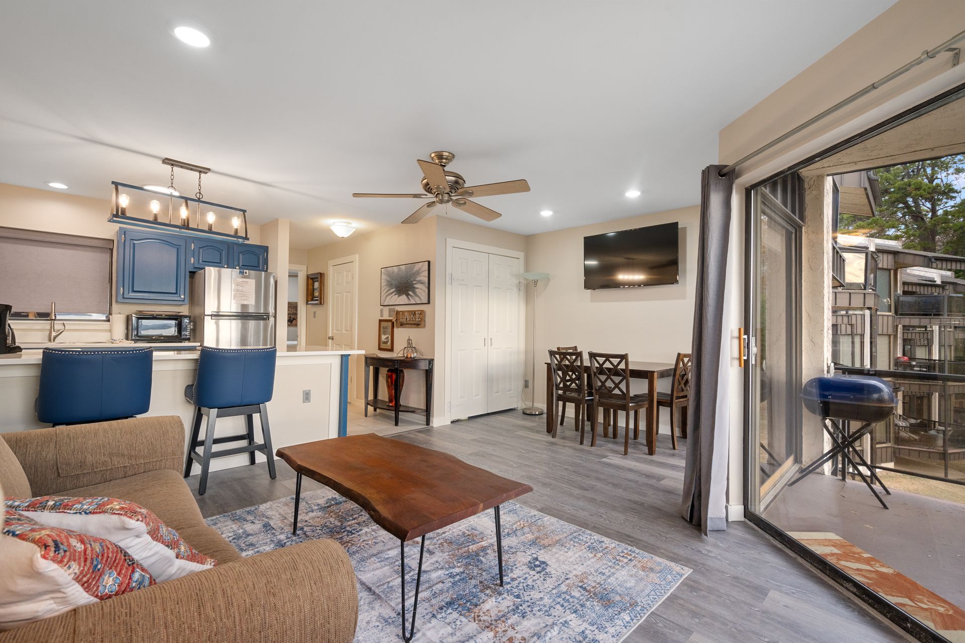 A living room with a couch , table , chairs and a ceiling fan.