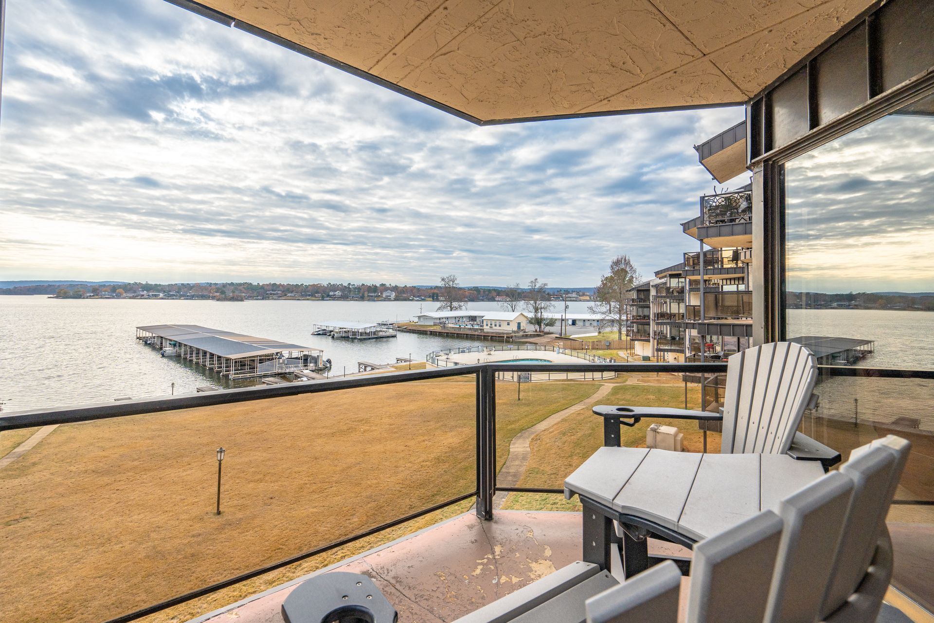 A balcony with chairs and a table overlooking a body of water.