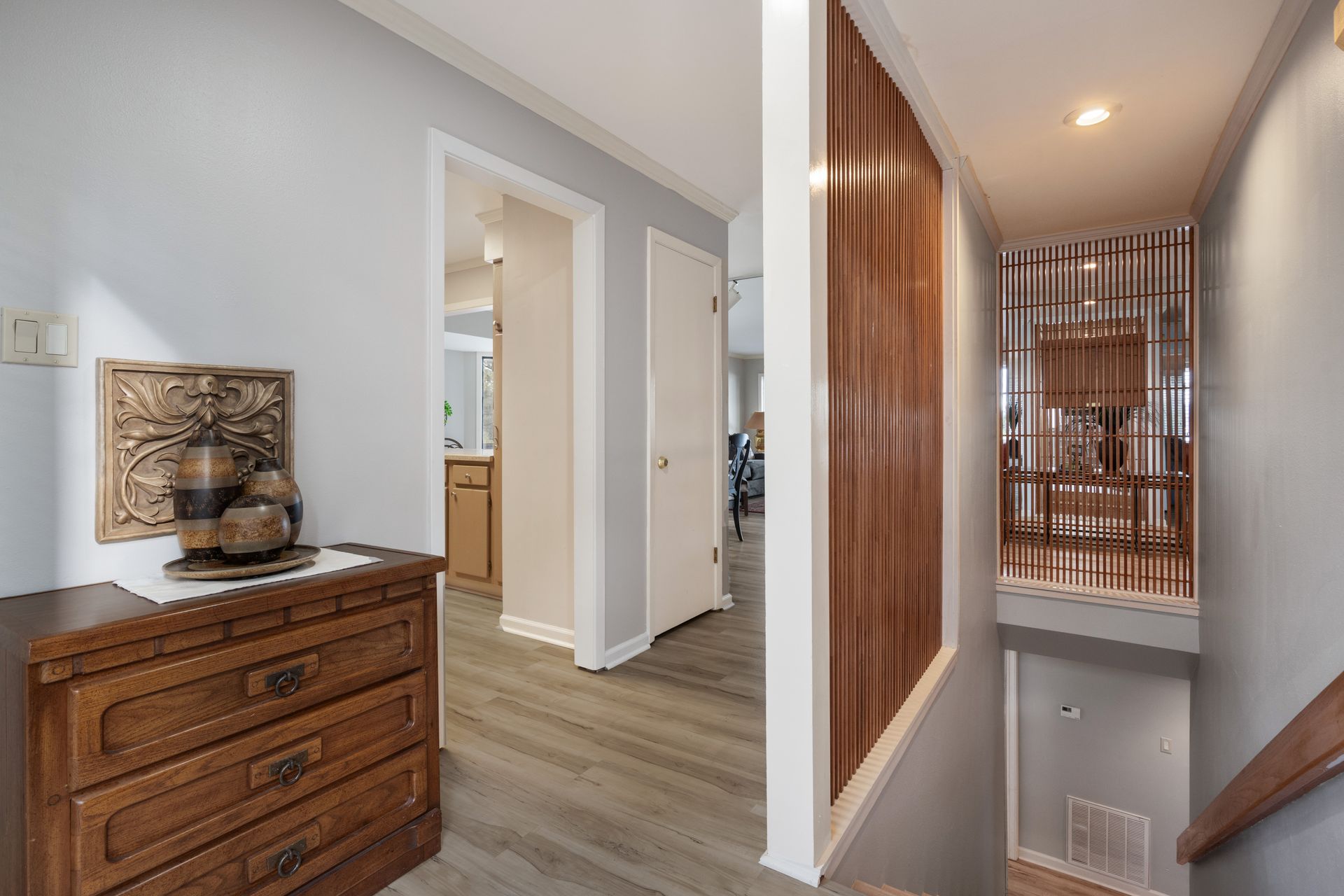 A hallway with a wooden dresser and stairs leading up to the second floor.
