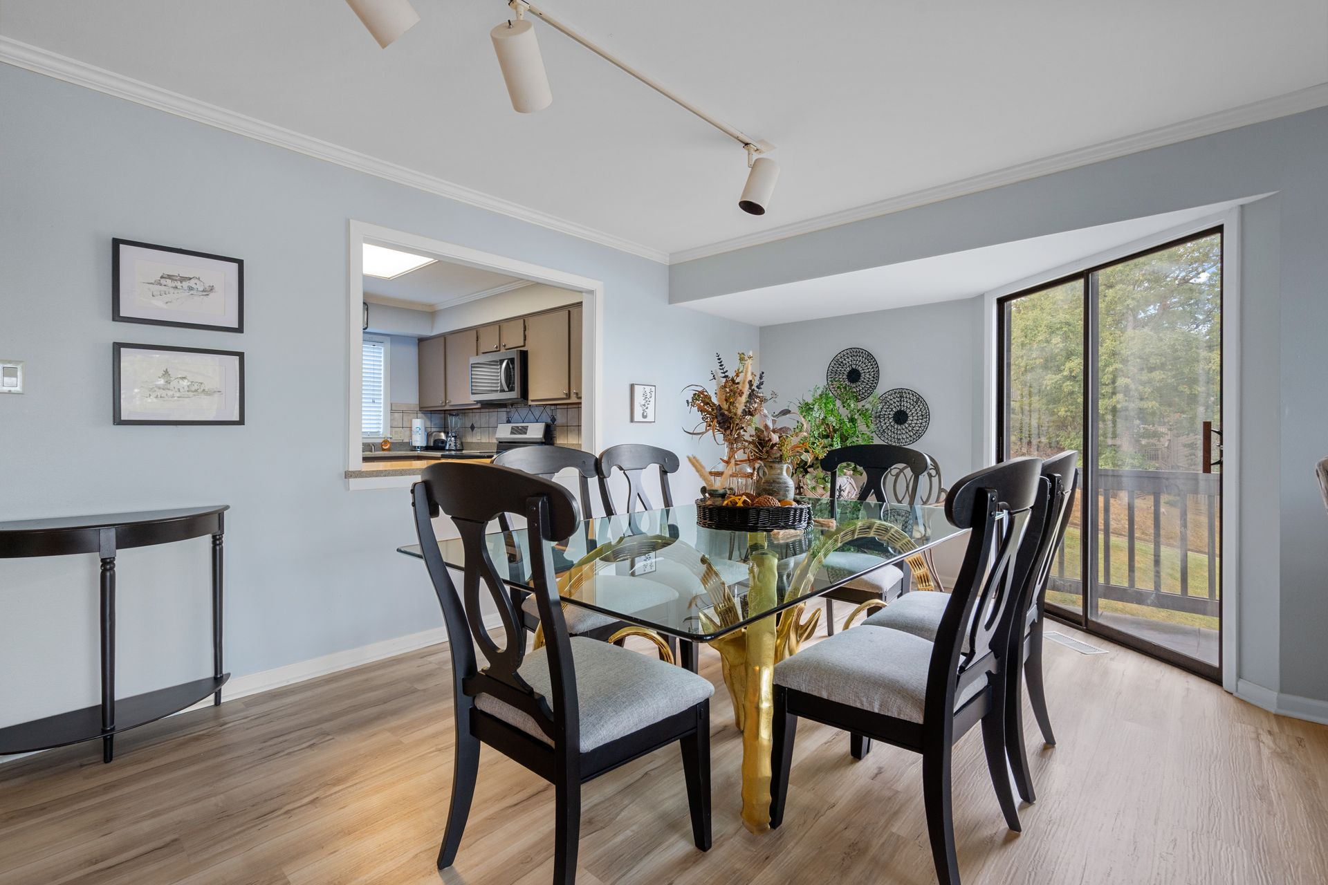 A dining room with a glass table and chairs and a sliding glass door.