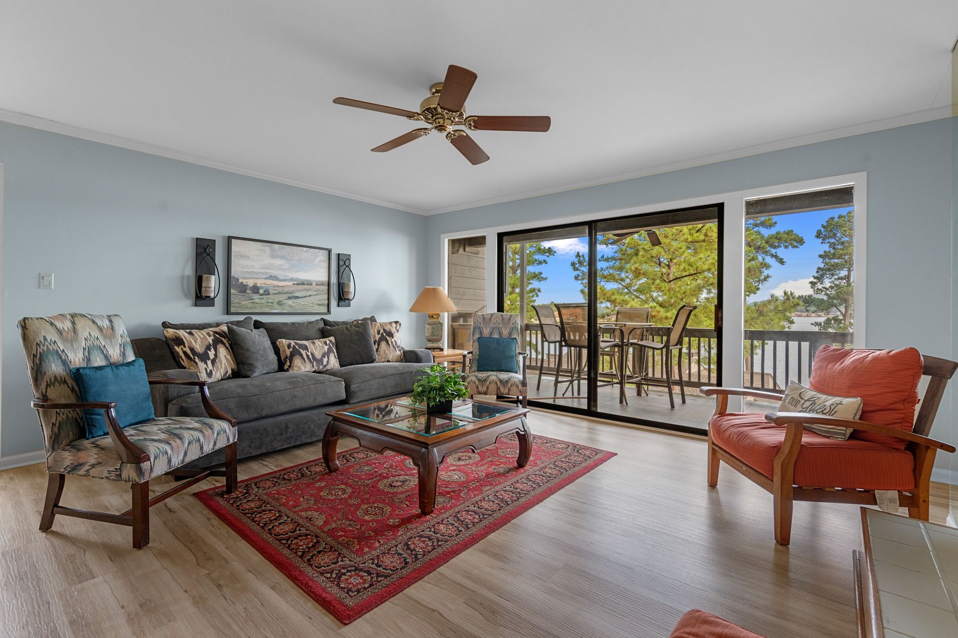 A living room with a couch , chairs , coffee table and ceiling fan.