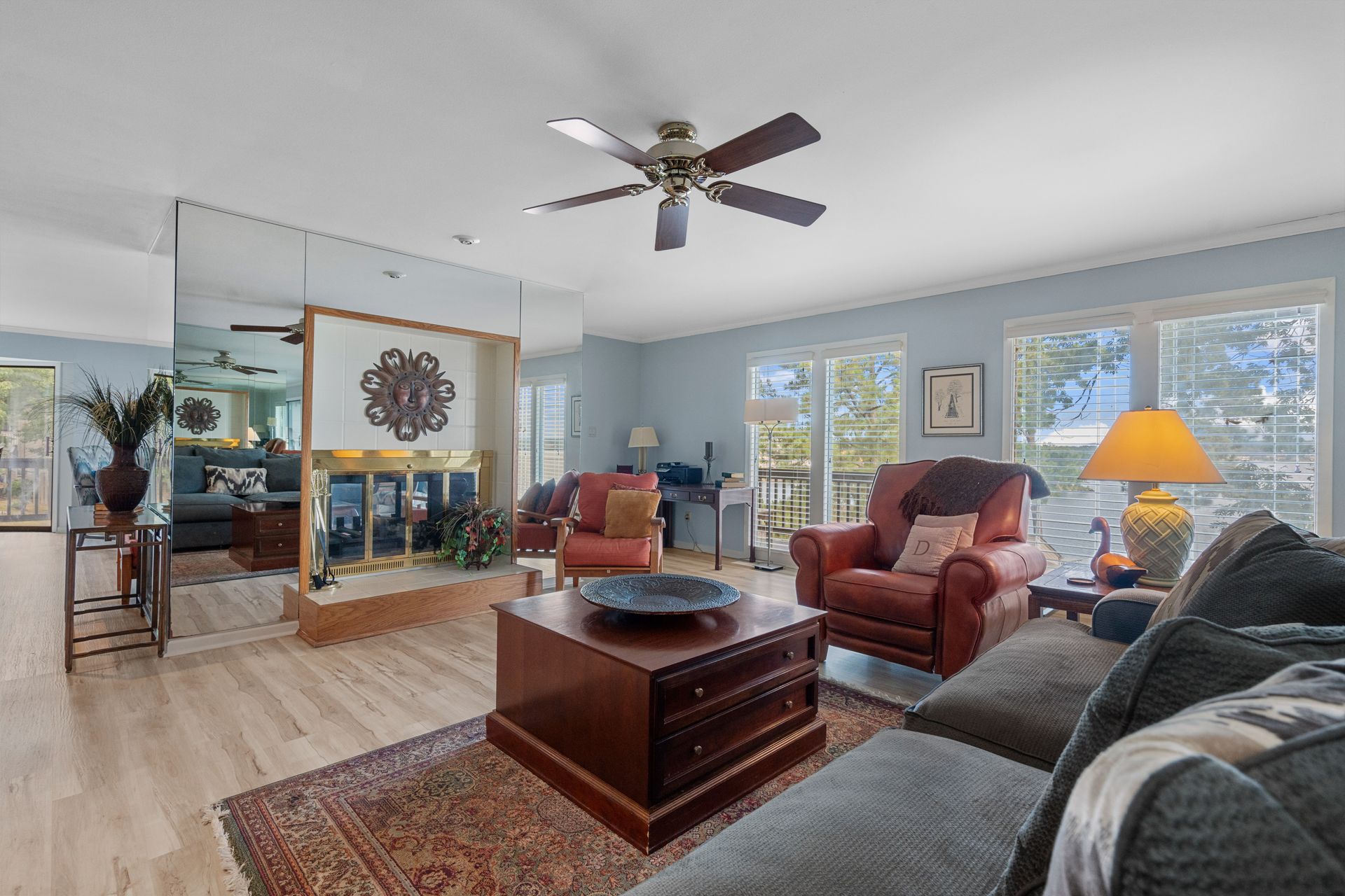 A living room with a couch , chairs , coffee table and ceiling fan.