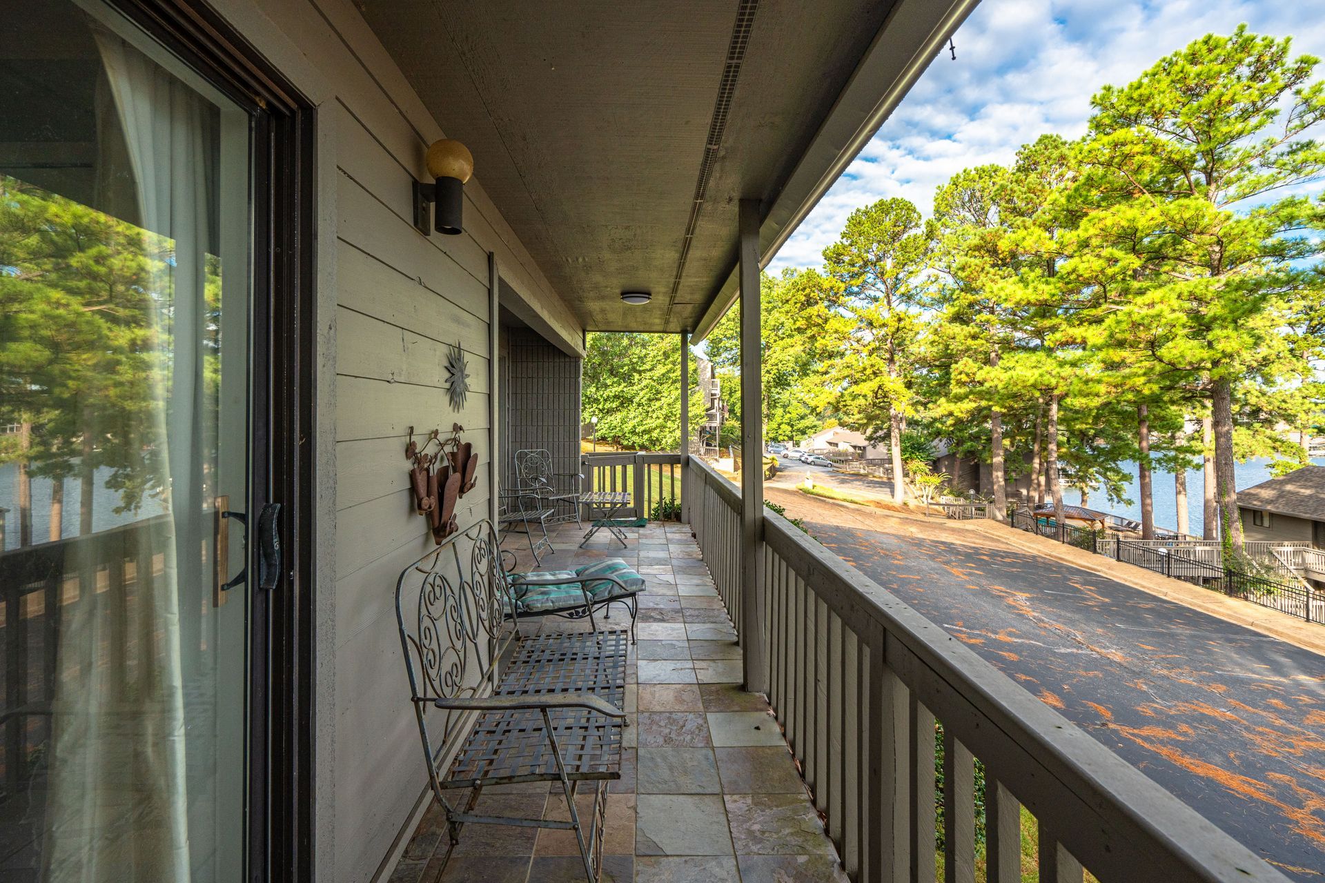 A balcony with a bench and chairs overlooking a lake.