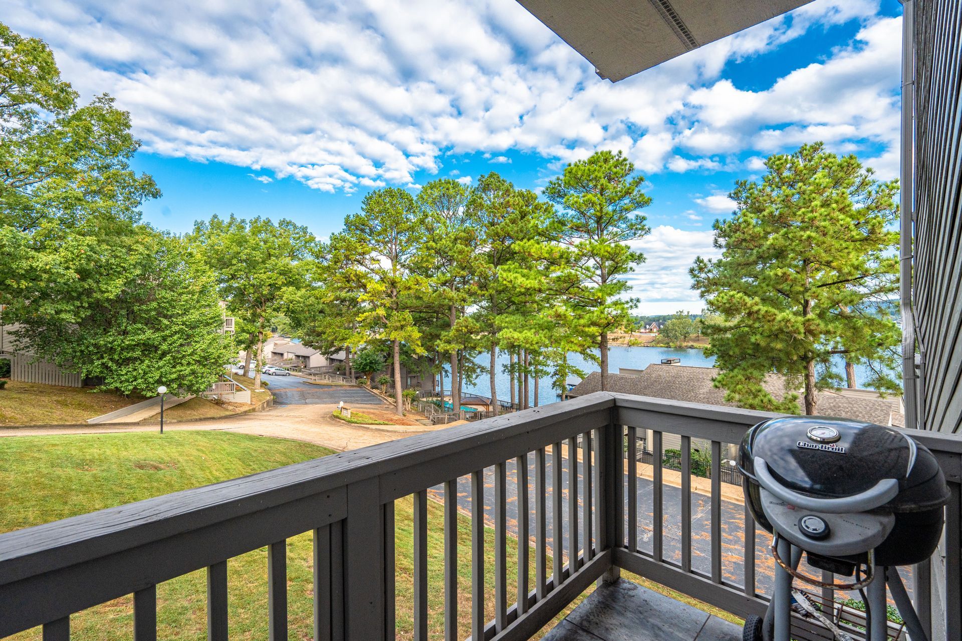 A balcony with a grill and a view of a lake.