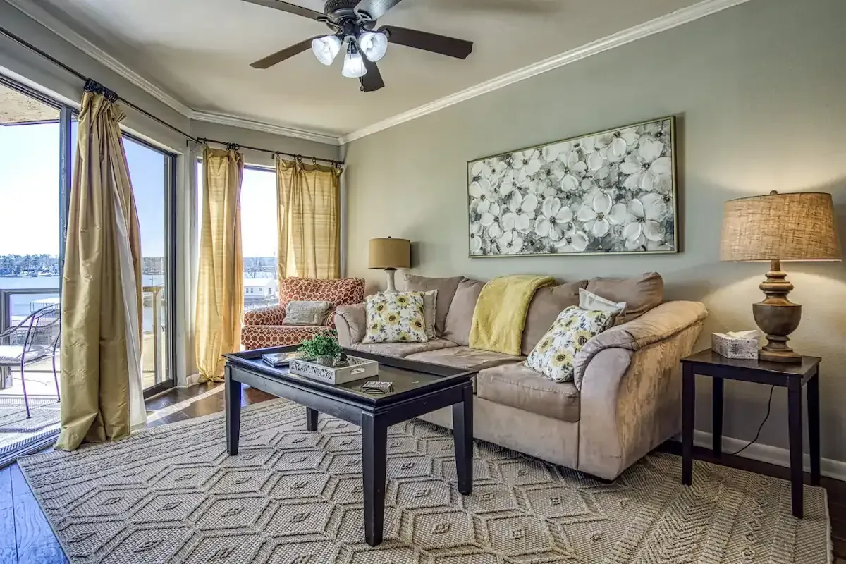 A living room with a couch , coffee table , lamps and a ceiling fan.