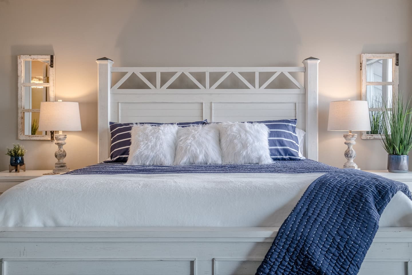 A bedroom with a bed , two lamps , and two mirrors.