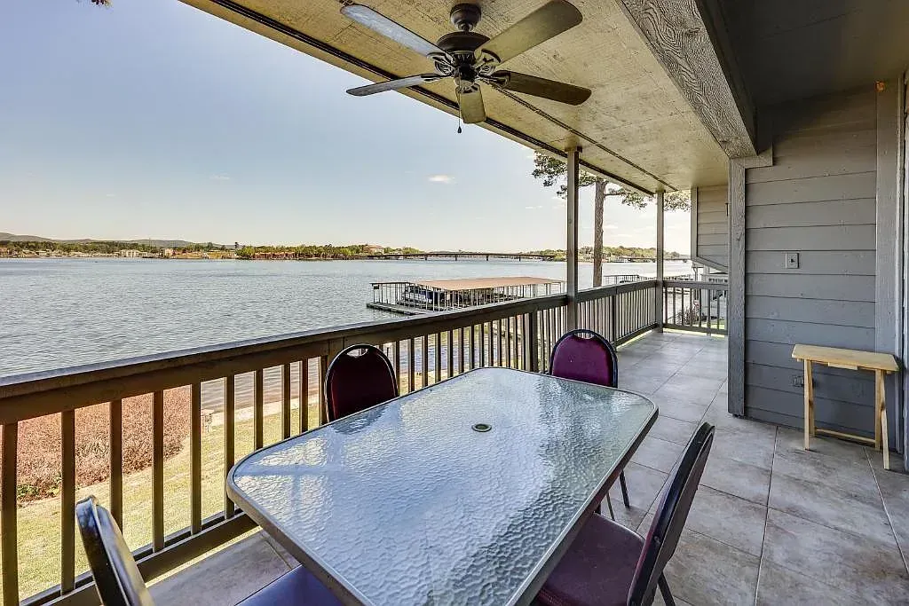 There is a table and chairs on the balcony overlooking the water.