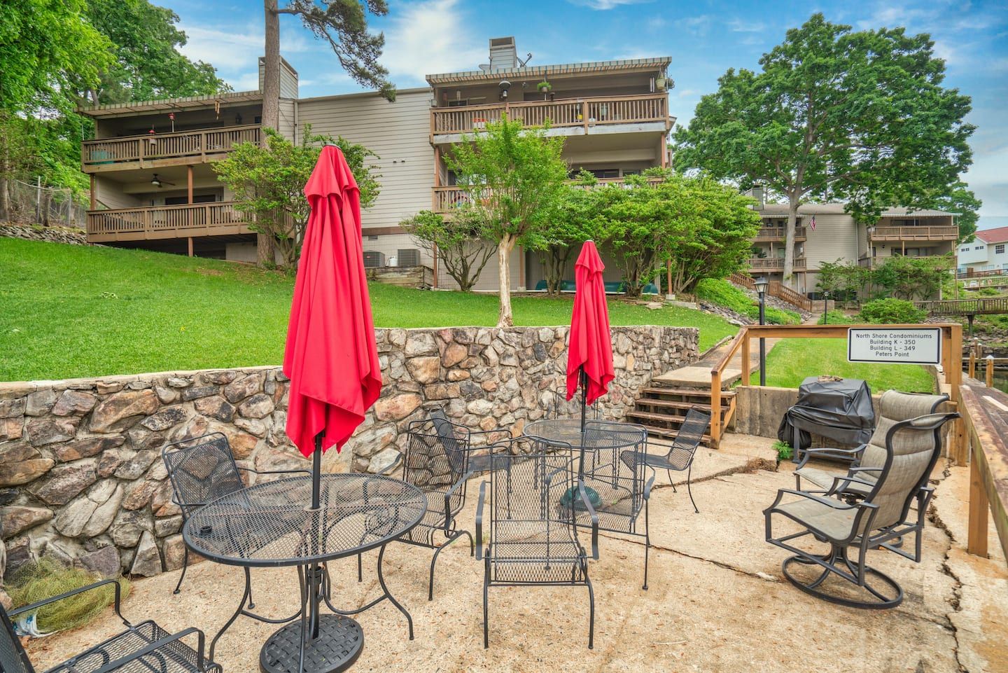 A patio with tables and chairs and red umbrellas in front of a building.