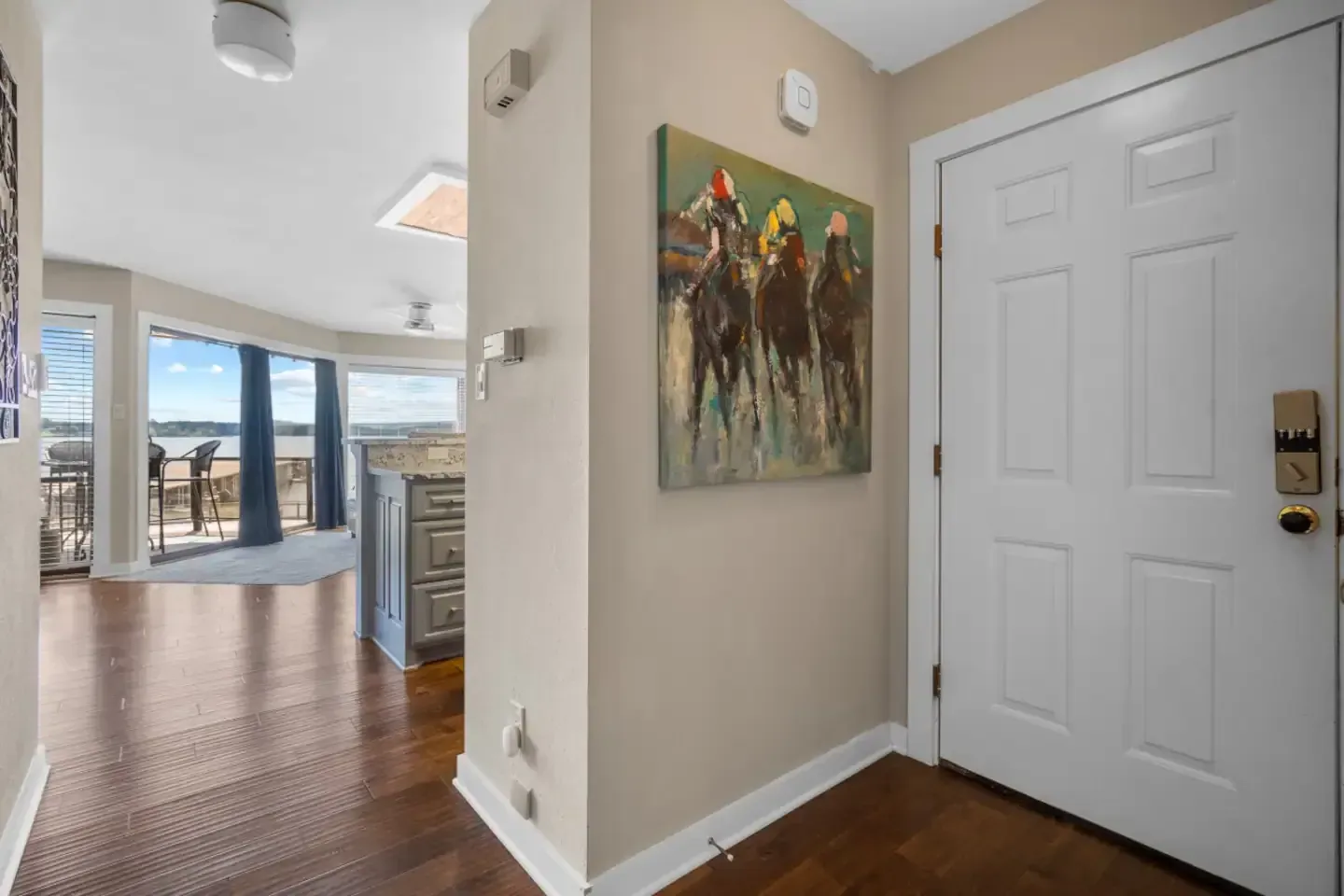 A hallway in a house with a painting of horses on the wall.