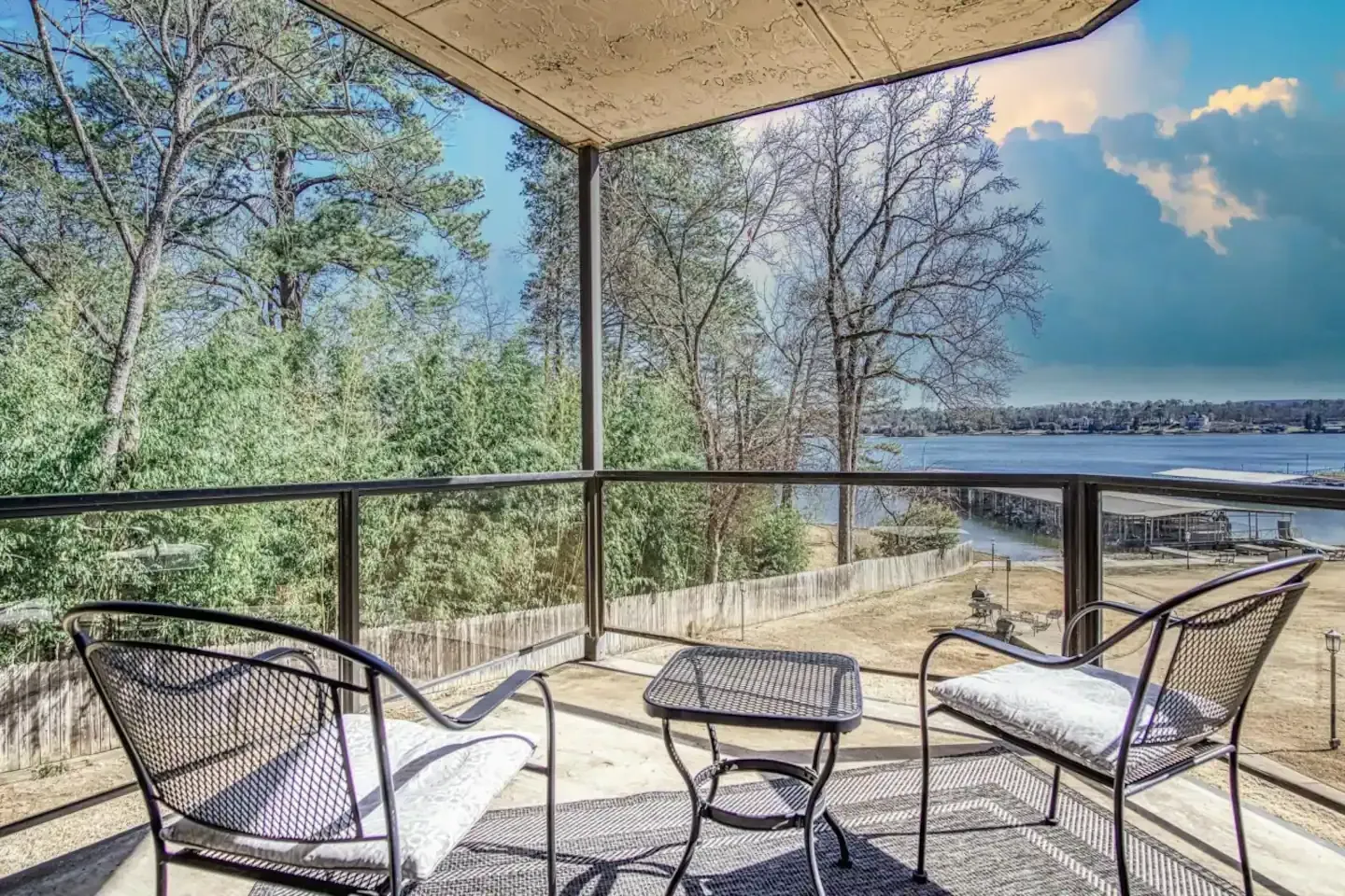 A balcony with two chairs and a table overlooking a body of water.