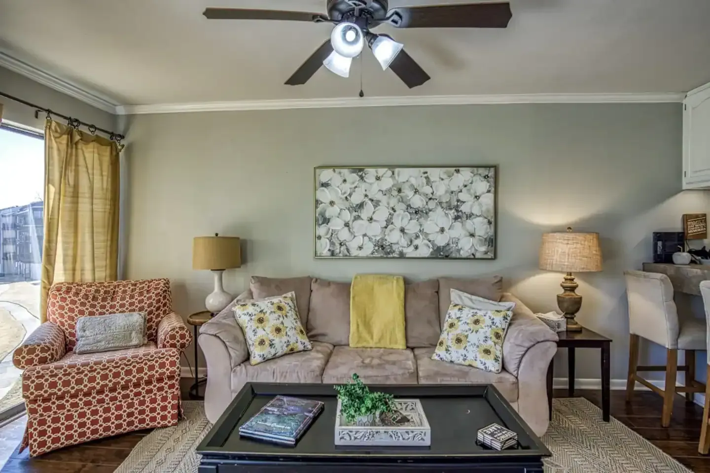 A living room with a couch , chair , coffee table and ceiling fan.