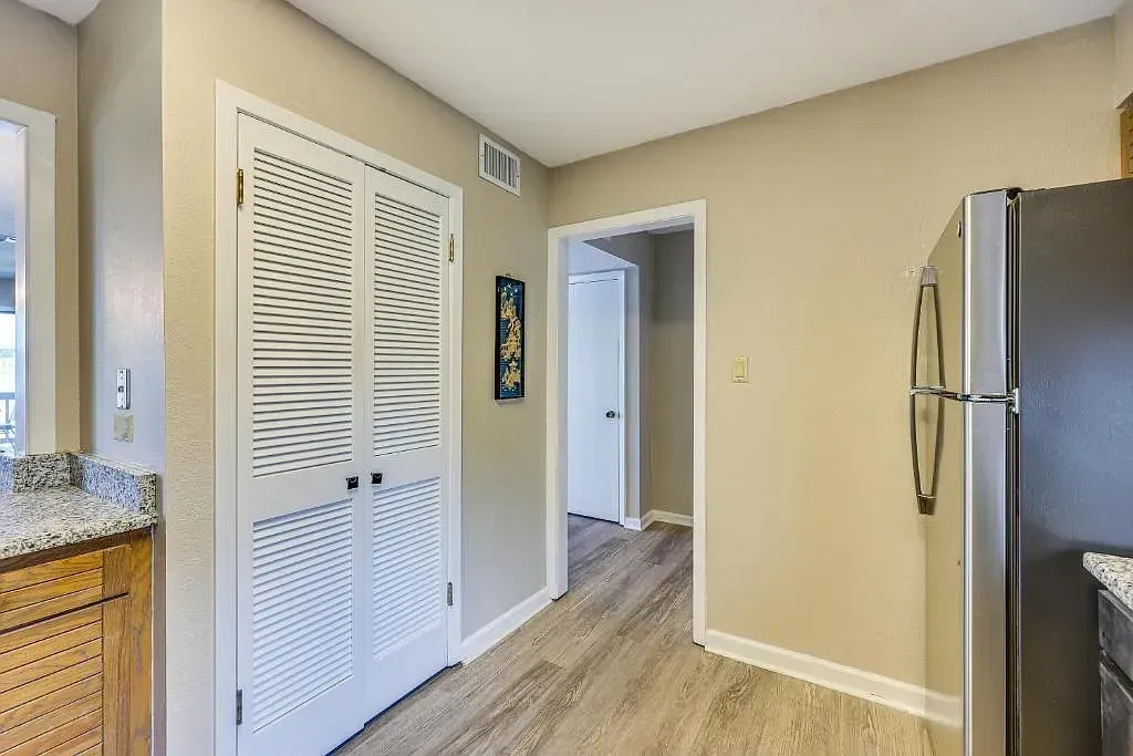 A hallway in a house with a refrigerator and a closet.