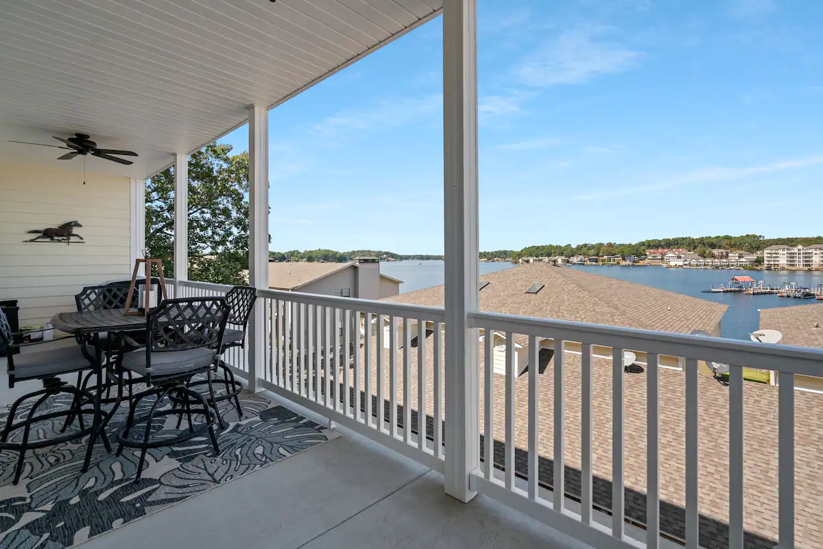 A balcony with a table and chairs overlooking a body of water.