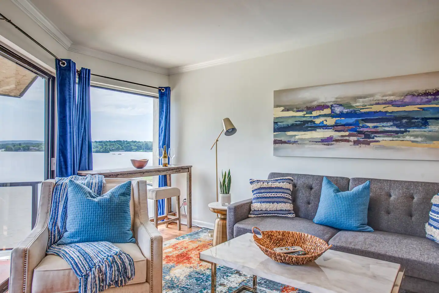 A living room with a couch , chair , coffee table and a painting on the wall.