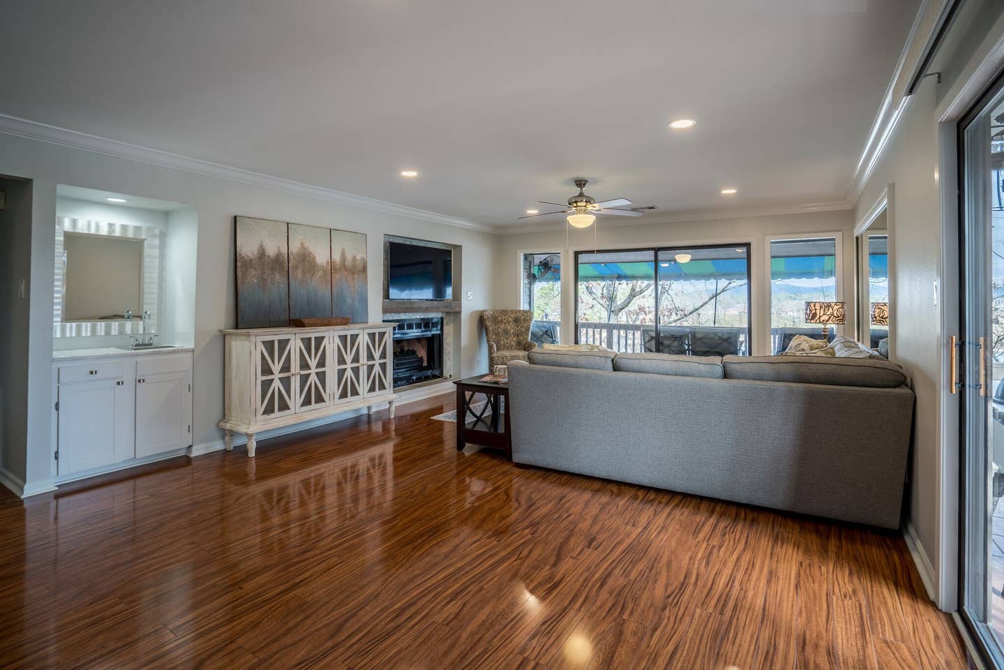 A living room with hardwood floors , a couch , a television and a fireplace.
