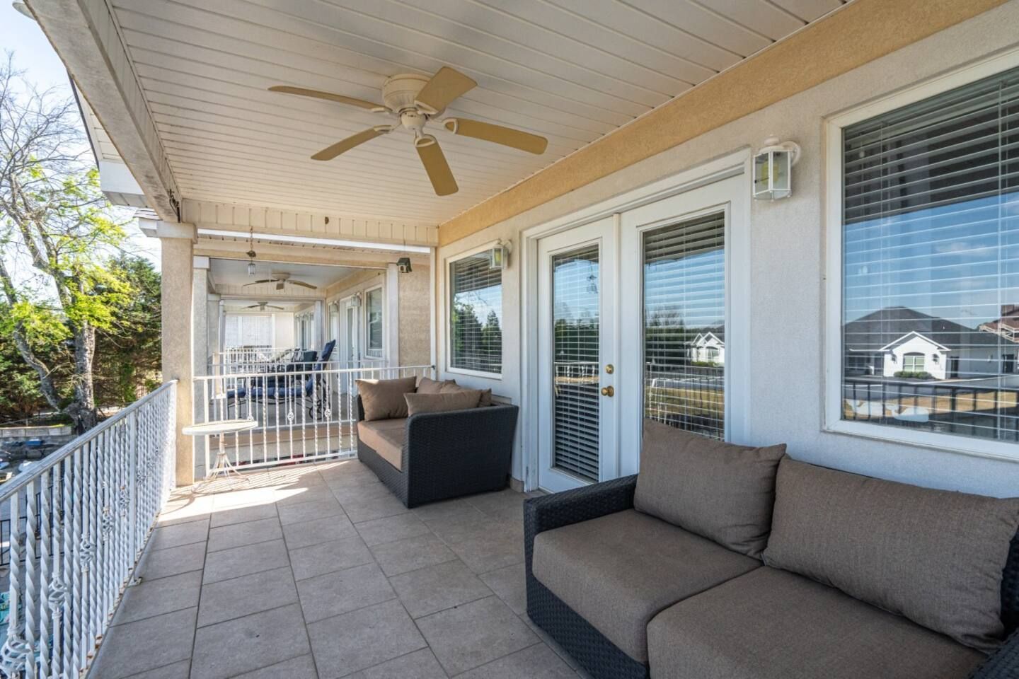 A large porch with a couch and a ceiling fan.