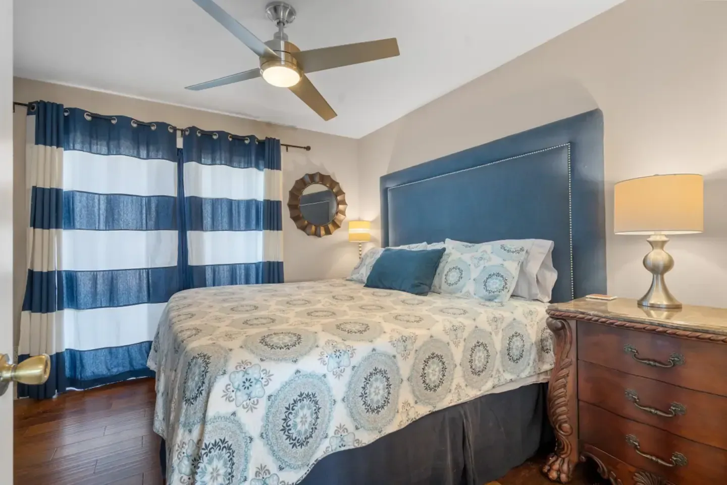 A bedroom with a bed , nightstand , lamp and ceiling fan.