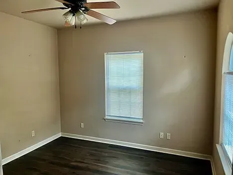 An empty bedroom with a ceiling fan and a window.