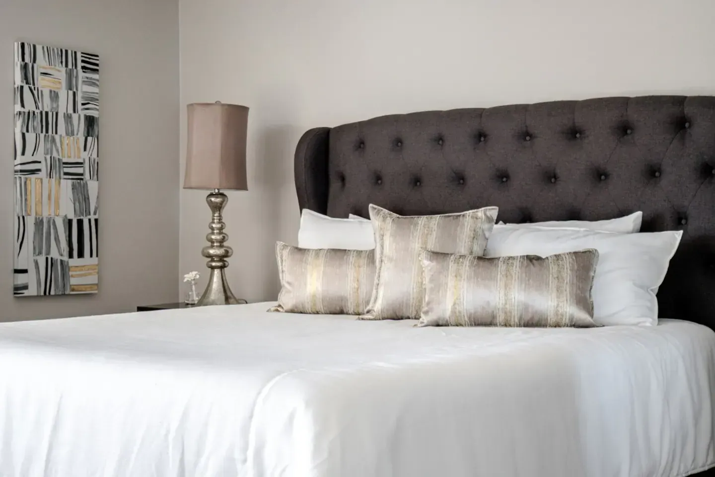 A bedroom with a bed , lamp , and painting on the wall.